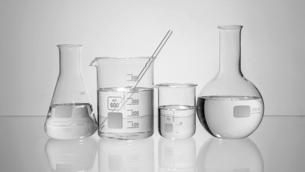 Laboratory beakers, cylinder, and flask with clear liquid, representing pharmaceutical and industrial research solutions from SBR International GmbH