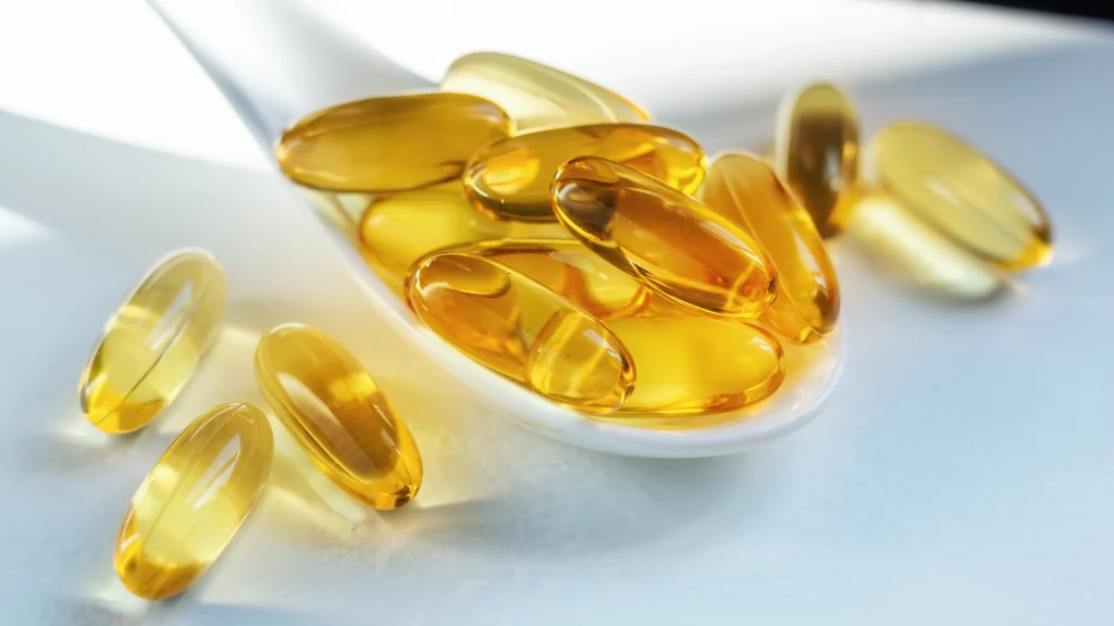 Golden softgel capsules with dietary supplements on a white background, symbolizing health and wellness