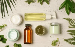 Flat lay of cosmetic containers with creams, oils, and natural leaves, representing personal care and cosmetic solutions from SBR International GmbH