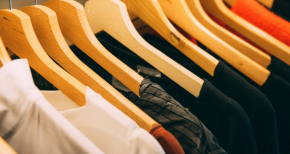 Row of colorful shirts on wooden hangers, symbolizing textile industry, fashion retail, and fabric treatments