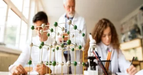 Students and scientist analyzing a molecular model in a laboratory, representing research, education, and innovation at SBR International GmbH